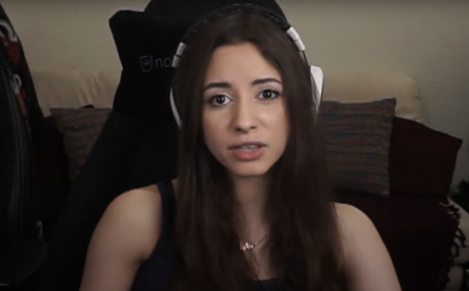 Anita with long hair wearing headphones is seated and speaking directly into the camera