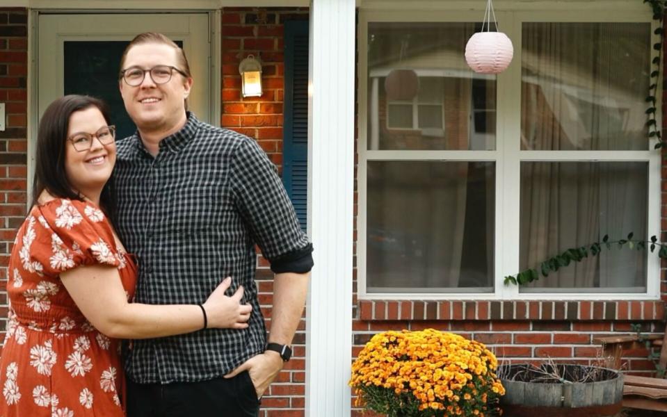 A woman and a man stand outside of home