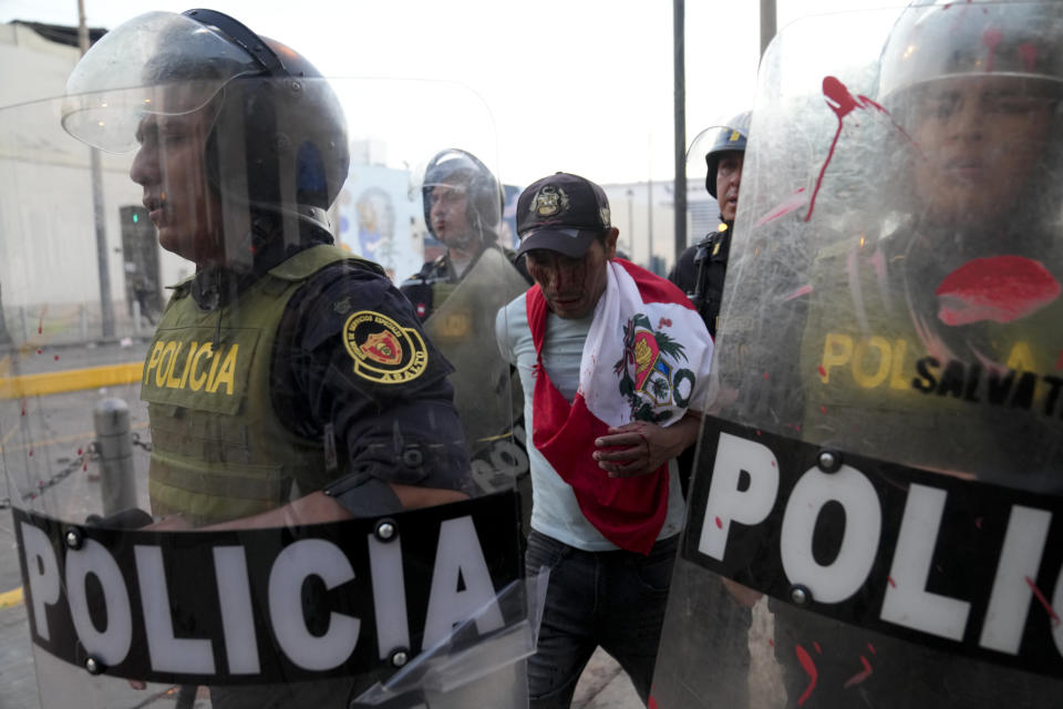 Police detain an anti-government protester in downtown Lima, Peru, Tuesday, Jan. 24, 2023. Protesters are seeking the resignation of President Dina Boluarte, the release from prison of ousted President Pedro Castillo, immediate elections and justice for demonstrators killed in clashes with police. (AP Photo/Martin Mejia)