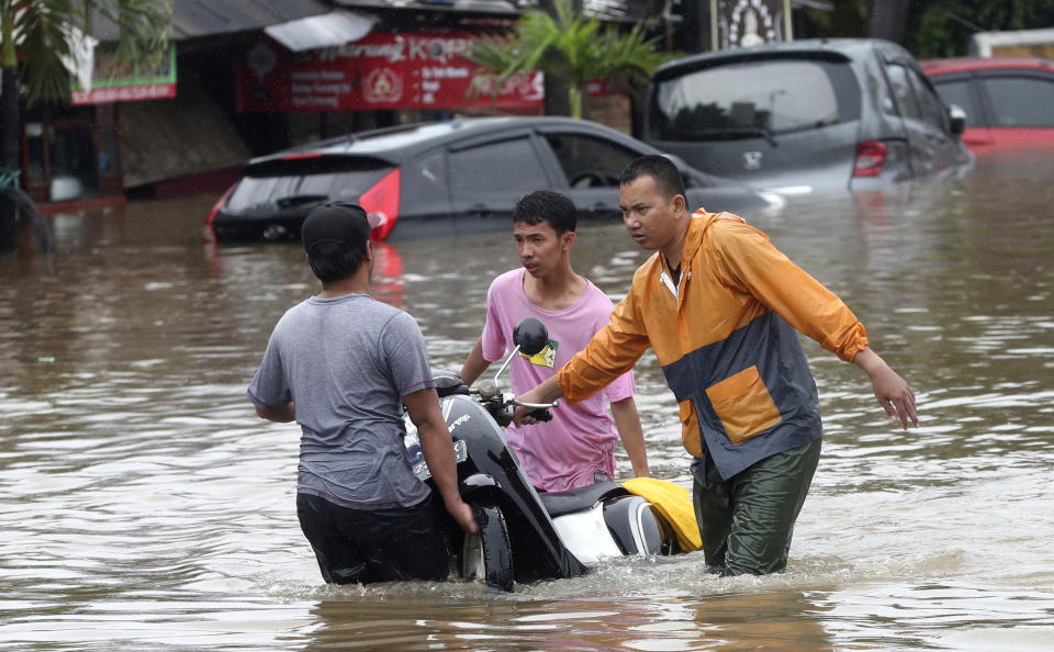 Indonesian people wade through floodwaters at Jatibening on the outskirt of Jakarta, Indonesia, Wednesday, Jan. 1, 2020. Severe flooding hit Indonesia's capital just after residents celebrating New Year's Eve, forcing a closure of an airport and thousands of inhabitants to flee their flooded homes. (AP Photo/Achmad Ibrahim)