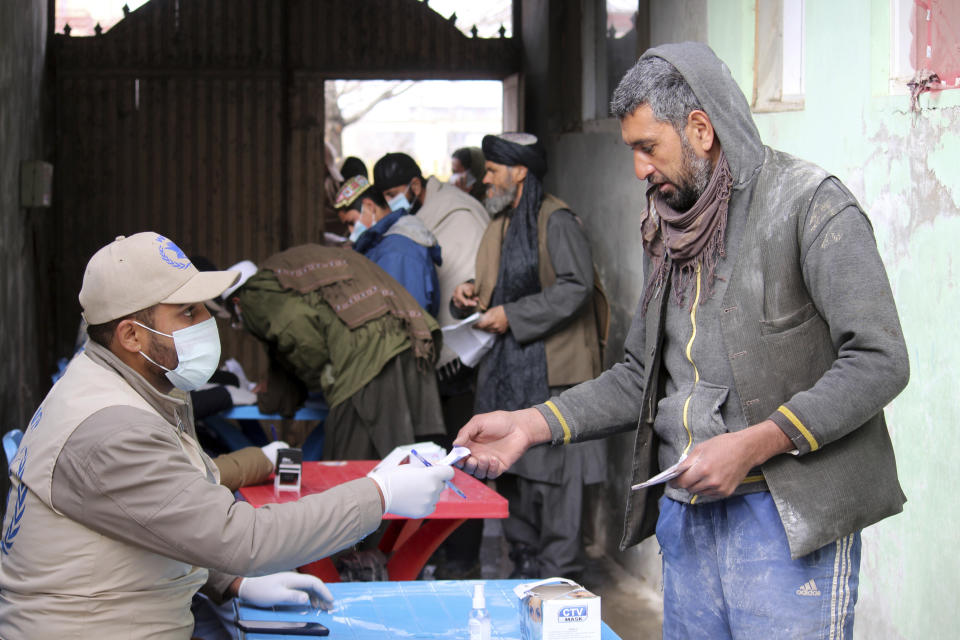 Afghans wait to receive food rations organized by the World Food Program (WFP) in Pul-e-Alam, the capital of Logar province. eastern of Afghanistan, Tuesday, Jan. 18, 2022. The Taliban's sweep to power in Afghanistan in August drove billions of dollars in international assistance out of the country and sent an already dirt-poor poor nation, ravaged by war, drought and floods, spiralling toward a humanitarian catastrophe. (AP Photo/Zubair Abassi)