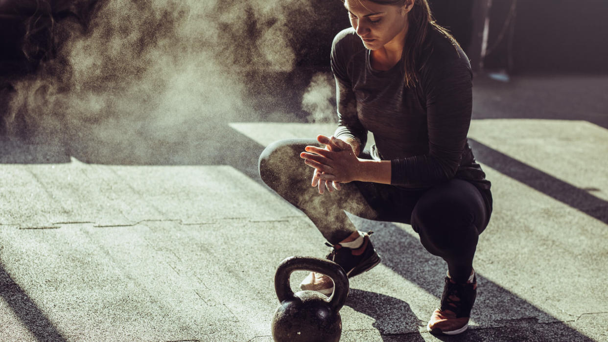 Young fit woman exercise with kettleball at gym.