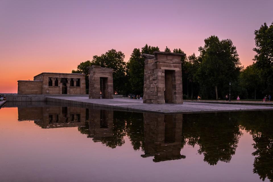 Historic Temple Of Debod Reflection In Pond Against Pink Sky During Sunset