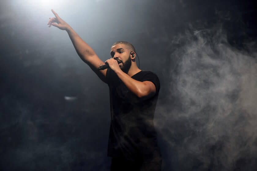 A man singing into a microphone and pointing on a stage