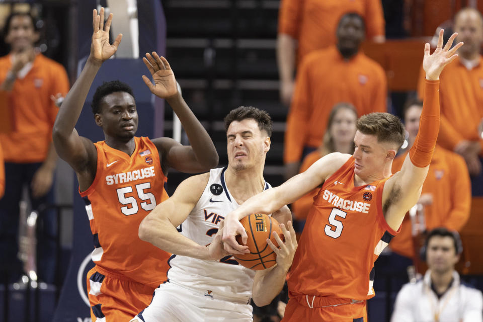 Virginia's Francisco Caffaro, center, tries to defend the ball against Syracuse players during the first half of an NCAA college basketball game in Charlottesville, Va., Saturday, Jan. 7, 2023. (AP Photo/Mike Kropf)