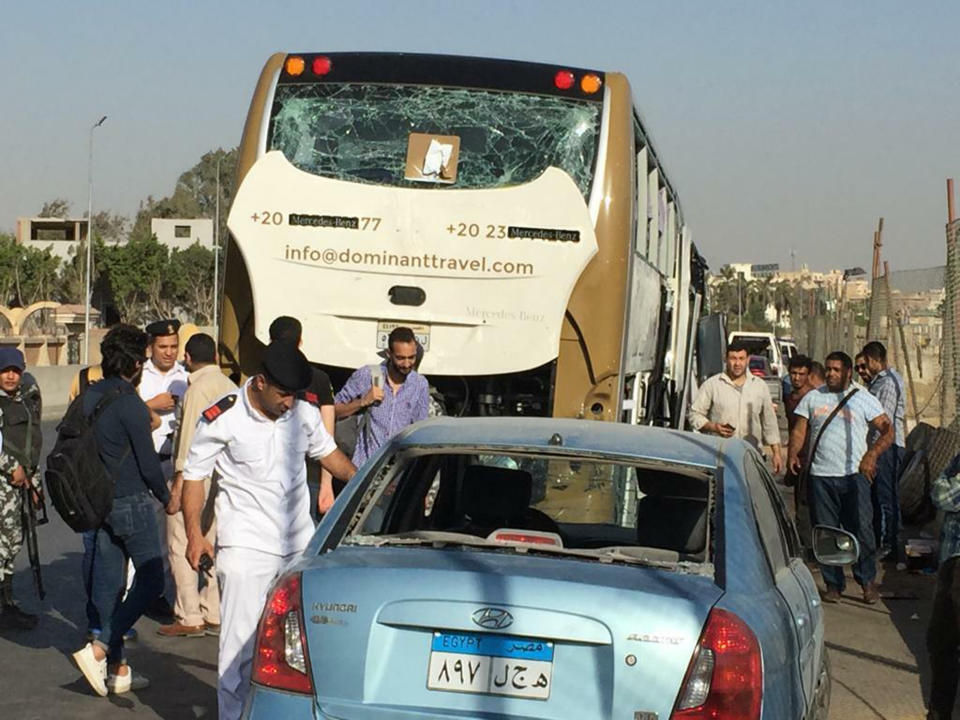 CORRECTS DATE PHOTO TAKEN - Police inspect a car and a bus that were damaged by a bomb, in Cairo, Egypt, Sunday, May 19, 2019. Egyptian officials say a roadside bomb has hit a tourist bus near the Giza Pyramids. They said Sunday’s blast wounded at least 17 people including tourists. (AP Photo/Mohammed Salah)