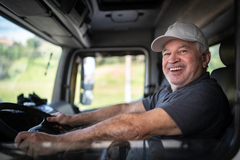 Smiling person in the driver's seat of a truck.