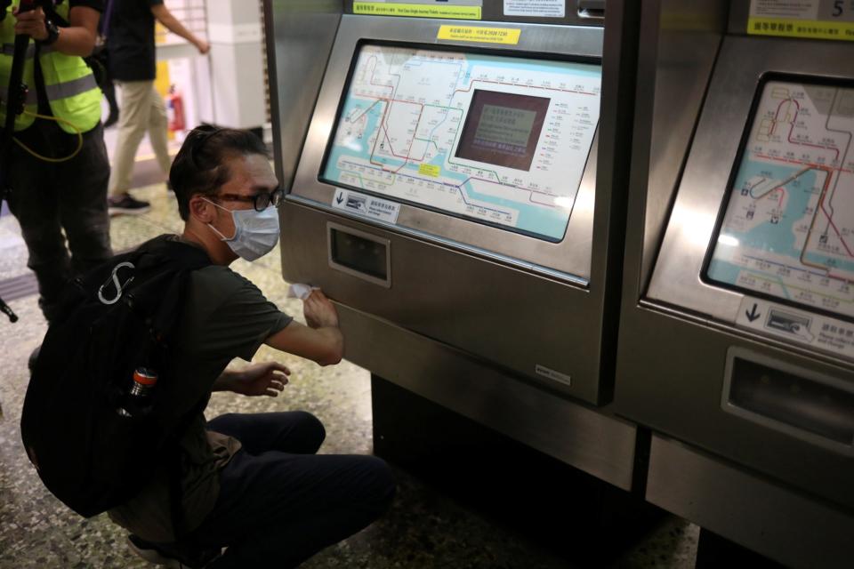 A member of the public cleans the ticket machine (Reuters)