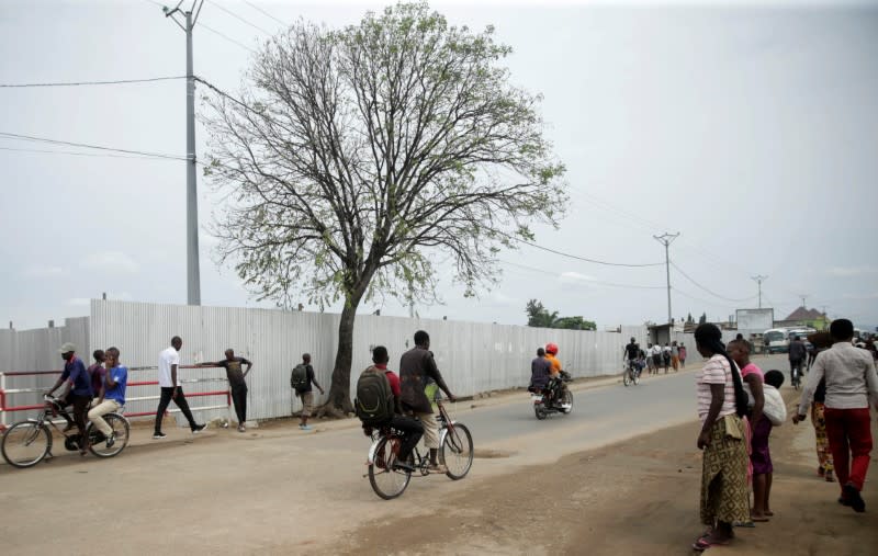 People walk around the area secured with iron-sheet fence where a mass grave was identified, in Kamenge neighbourhood, Bujumbura