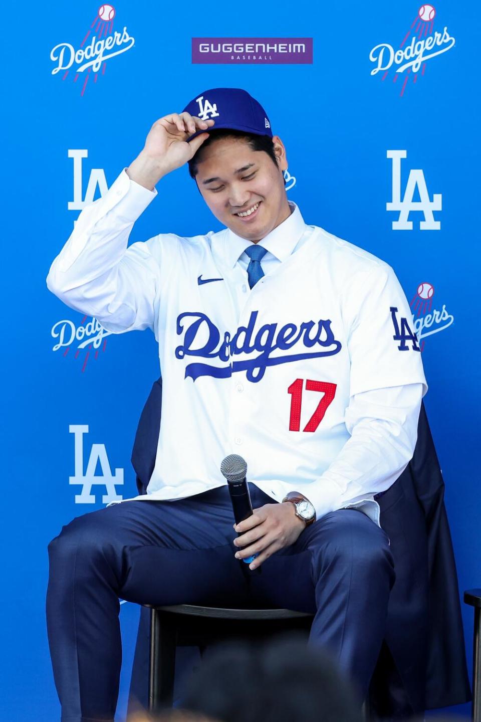 Shohei Ohtani adjusts his Dodgers hat as he is introduced as the newest player of the Dodgers