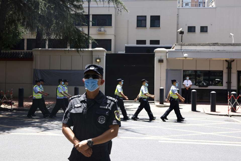 Policías chinos marchando ante el antiguo consulado estadounidense en Chengdu, en la provincia suroccidental china de Sichuan, el lunes 27 de julio de 2020. (AP Foto/Ng Han Guan)