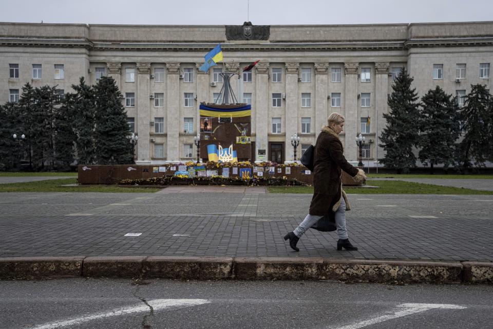 A woman walks in front of regional administration building at the city center of Kherson, Ukraine, Saturday, Dec. 10, 2022. (AP Photo/Evgeniy Maloletka)