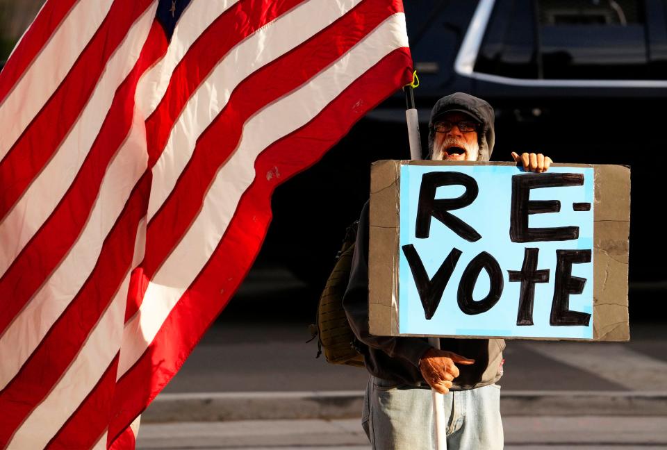 A protester stands outside of the Maricopa County Board of Supervisors general election canvass special meeting on Nov. 28, 2022, in Phoenix, Ariz.