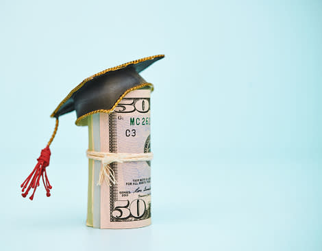 an image of a roll of 50-dollar bills topped by a graduation cap