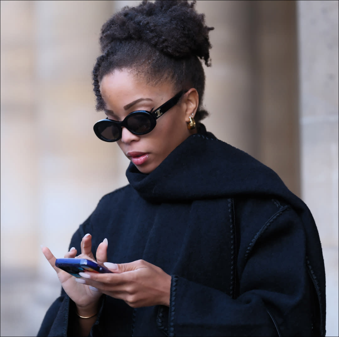  Llie Delphine wears Celine sunglasses, a black oversized wool scarf, a black coat from Toteme, black cropped pants, during a street style fashion photo session, on November 06, 2023 in Paris, France. (Photo by Edward Berthelot/Getty Images). 