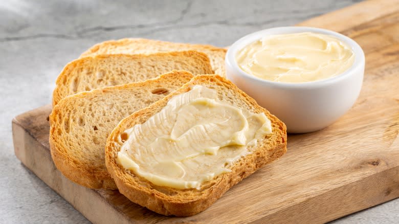 toast on wooden borad with white container of butter