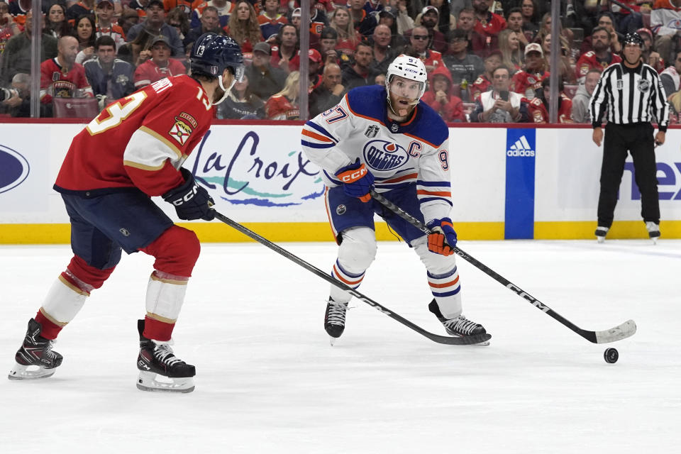 Edmonton Oilers center Connor McDavid (97) skates with the puck as Florida Panthers center Sam Reinhart (13) defends during the third period of Game 1 of the NHL hockey Stanley Cup Finals, Saturday, June 8, 2024, in Sunrise, Fla. (AP Photo/Wilfredo Lee)