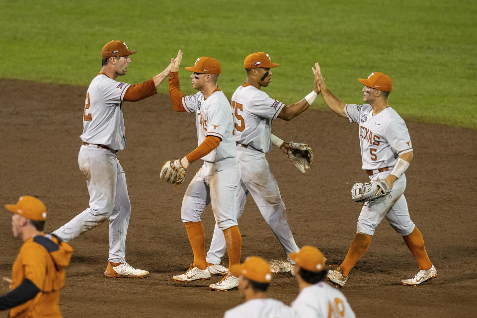 Texas Zach Zubia (52) and Eric Kennedy (30), and Camryn Williams (55) and Mike Antico (5) give each other a high five celebrating their win over Virginia during a baseball game in the College World Series Thursday, June 24, 2021, at TD Ameritrade Park in Omaha, Neb. (AP Photo/John Peterson)