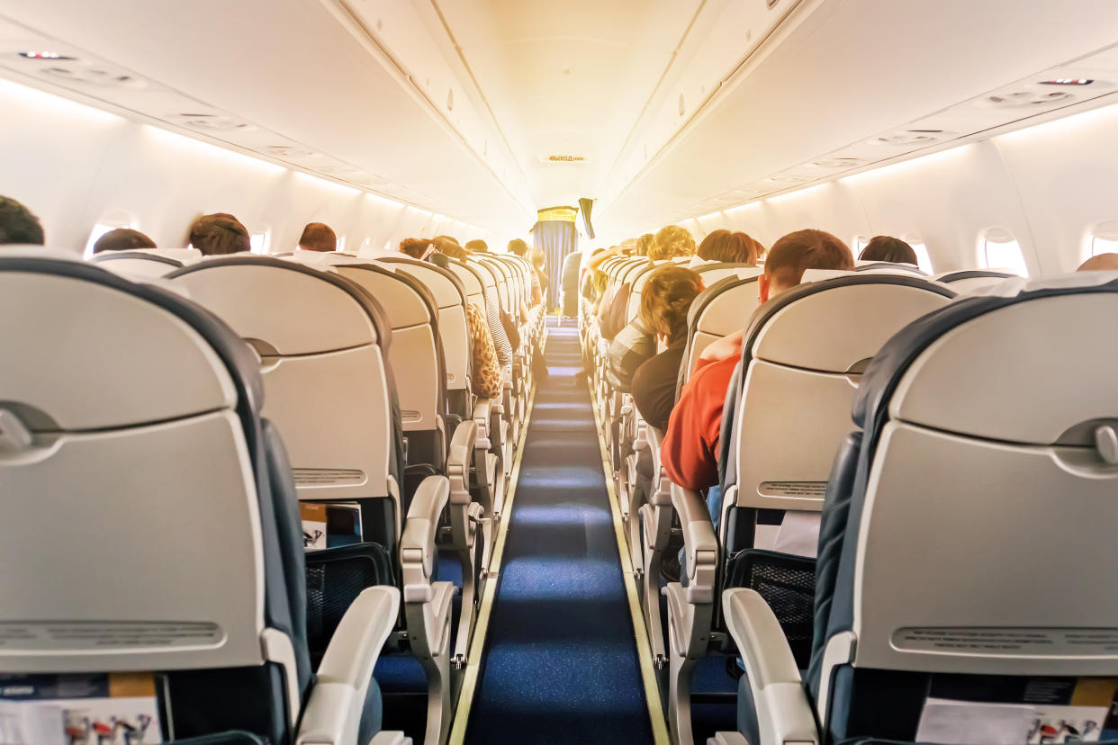 Commercial aircraft cabin with rows of seats down the aisle. morning light in the salon of the airliner. economy class