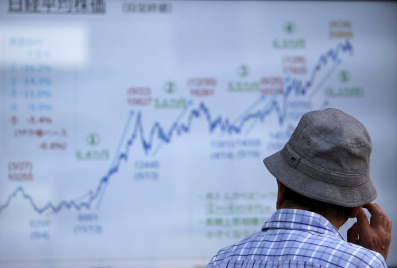 A man looks at an electronic graph showing recent movement of Japan's Nikke share average outside a brokerage in Tokyo July 13, 2015. REUTERS/Issei Kato