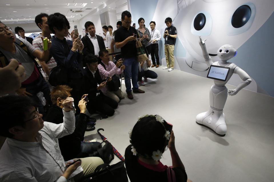 SoftBank Corp's human-like robots named 'pepper' dances and sings a song as people take pictures at its branch in Tokyo