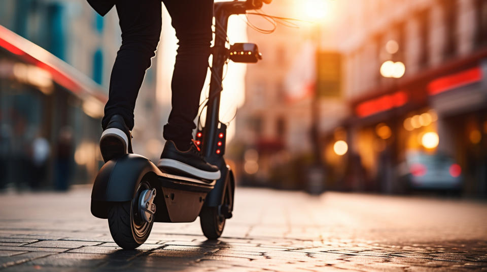 A close-up of a person riding a two-wheeled electric vehicle, against modern street backdrop.