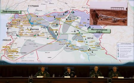 Russian Defence Ministry officials sit under a display showing the Turkish-Syrian border during a briefing in Moscow, Russia, December 2, 2015. REUTERS/Sergei Karpukhin