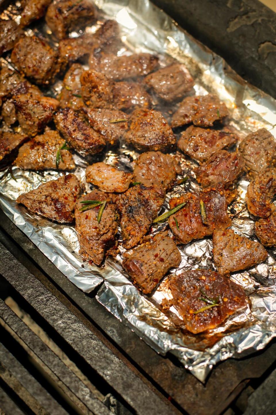 Pieces of beef being grilled on foil