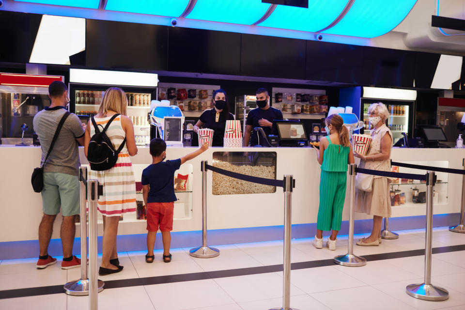 Family and worker at a cinema concession stand, with popcorn in the foreground