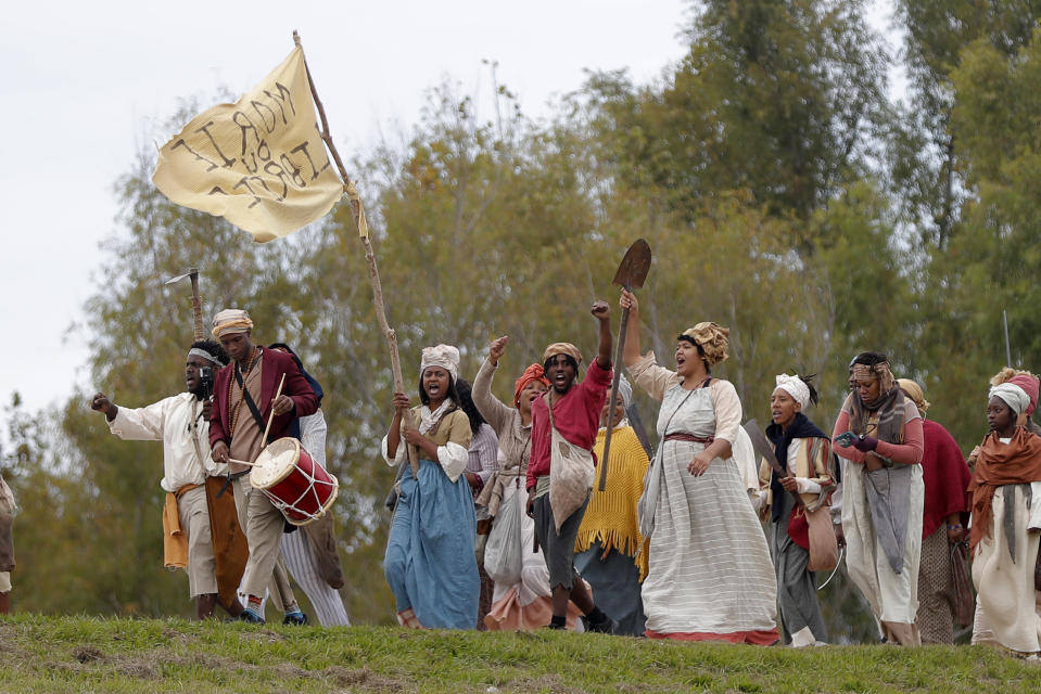 People march along the Mississippi River levee as they participate in a performance artwork reenacting the largest slave rebellion in U.S. history, in LaPlace, La., Friday, Nov. 8, 2019. The reenactment was conceived by Dread Scott, an artist who often tackles issues of racial oppression and injustice. Scott says that those who took part in the rebellion were "heroic" and that the rebellion is something that people should know about and be inspired by. (AP Photo/Gerald Herbert)