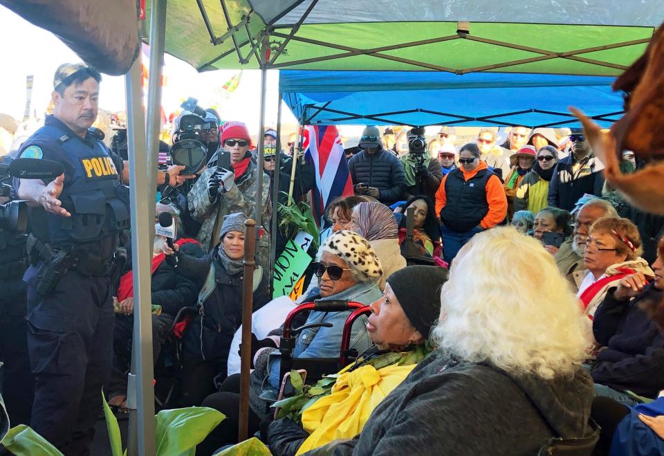 Officers from the Hawaii Department of Land and Natural Resources prepare to arrest protesters, many of them elderly, who are blocking a road to prevent construction of a giant telescope on a mountain that some Native Hawaiians consider sacred, on Mauna Kea on the Big Island of Hawaii.