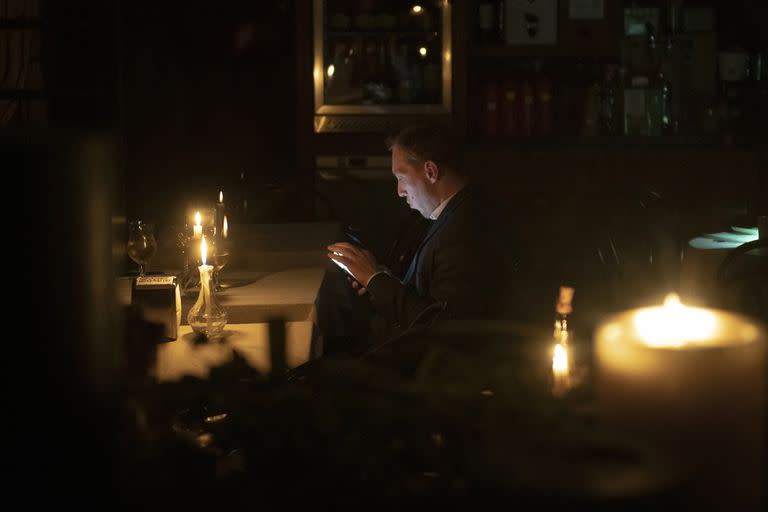 Un hombre, sentado en una cafetería durante un apagón en Kiev, Ucrania, el 4 de noviembre de  2022. (AP Foto/Andrew Kravchenko)