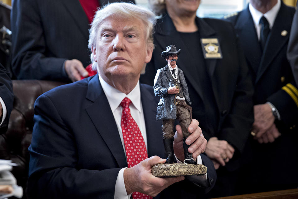 <p>U.S. President Donald Trump holds up a statue he received as a gift while meeting with county sheriffs in the Oval Office of the White House on February 7, 2017 in Washington, D.C. (Andrew Harrer – Pool/Getty Images) </p>