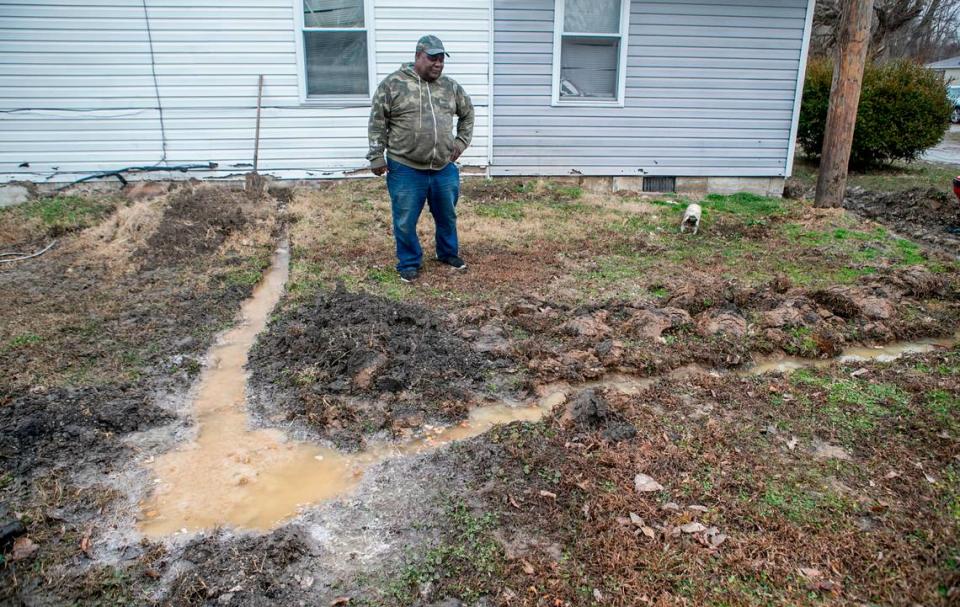 In this 2020 file photo, Cahokia Heights resident Walter Byrd stands in his yard next to raw sewage and his attempt to keep the sewage from backing up into his home.