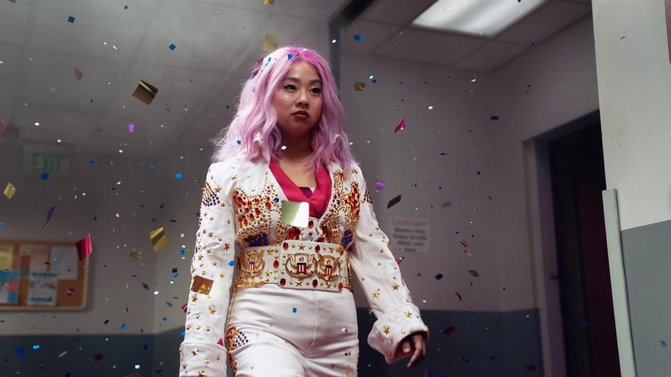 Stephanie Hsu walks down the hall in an Elvis costume