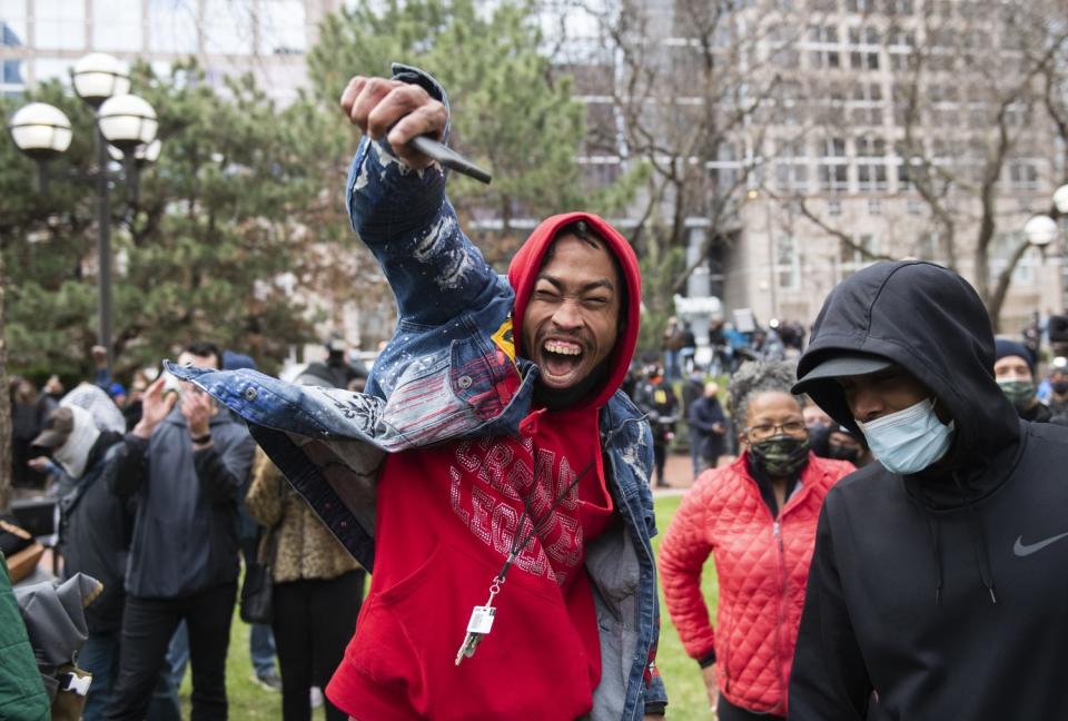 A jubilant man in a red hoodie, left, raises his hand next to another person in a black hoodie