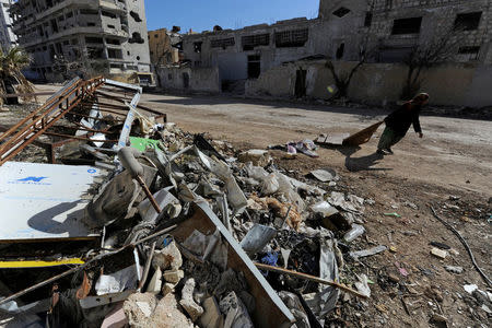 A woman walks past debris along a street in Aleppo's Belleramoun Industrial Zone, Syria February 2, 2017. REUTERS/Omar Sanadiki