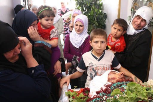 Relatives of Syrian Abu Ismail, who was allegedly killed by a government sniper, mourn over his body during a funeral procession in the city of Qusayr