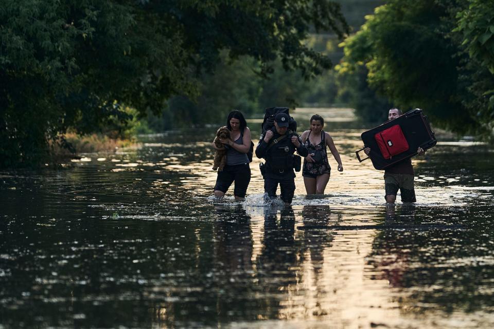 Local residents carry their belongings as they evacuate from a flooded neighborhood in Kherson, Ukraine, on June 6, 2023