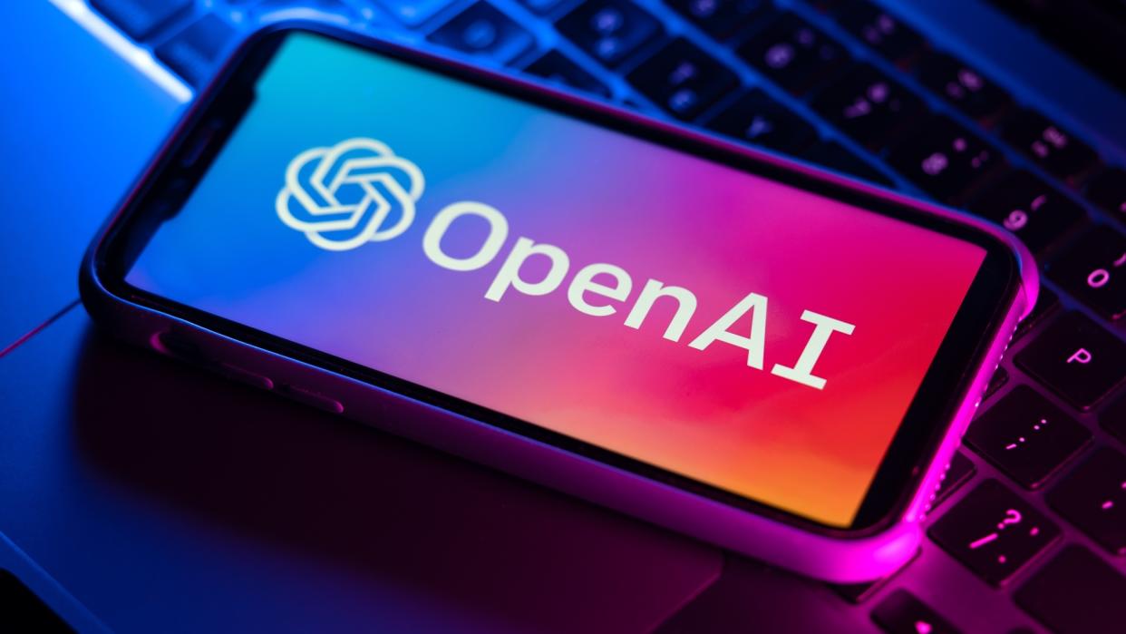  OpenAI logo on phone sitting on top of laptop keyboard. 