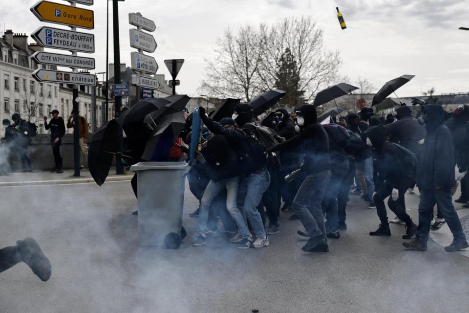 Youths scuffle with police forces amid tear gas during a demonstration in Nantes (AP)