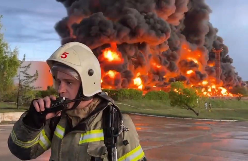 FILE - In this handout photo made from video released by the Governor of Sevastopol Mikhail Razvozhaev telegram channel on Saturday, April 29, 2023, a firefighter speaks on the walkie talkie as smoke and flame rise from a burning fuel tank after it was hit by a drone, a Russian-appointed official there reported, in Sevastopol, Crimea. The Crimean Peninsula's balmy beaches have been vacation spots for Russian czars and has hosted history-shaking meetings of world leaders. And it has been the site of ethnic persecutions, forced deportations and political repression. Now, as Russia’s war in Ukraine enters its 18th month, the Black Sea peninsula is again both a playground and a battleground. (Sevastopol Governor Mikhail Razvozhaev telegram channel via AP, File)