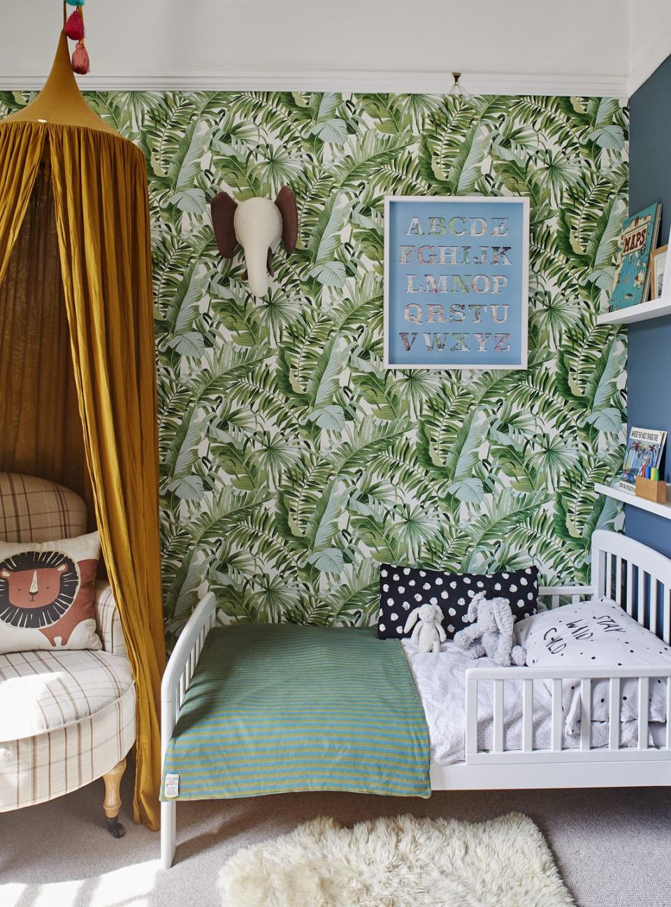 children's bedroom with tropical palm print wallpaper and yellow canopy