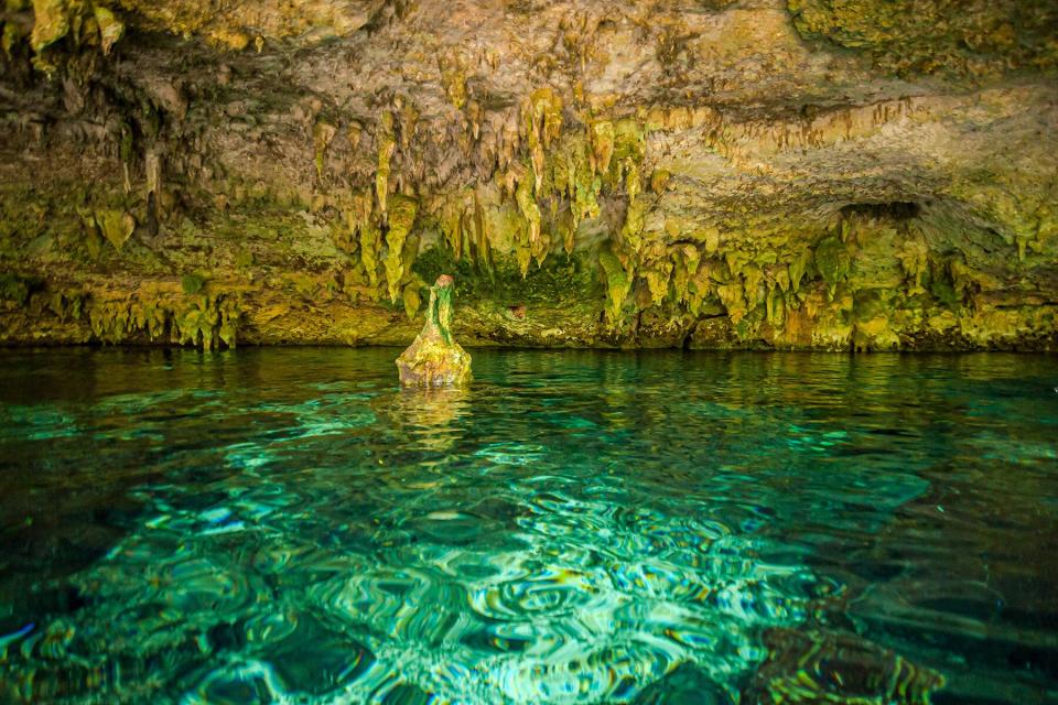 View of the transparent clean water of the Dos Ojos Cenote, a cave filled with water, rocks and stalactites