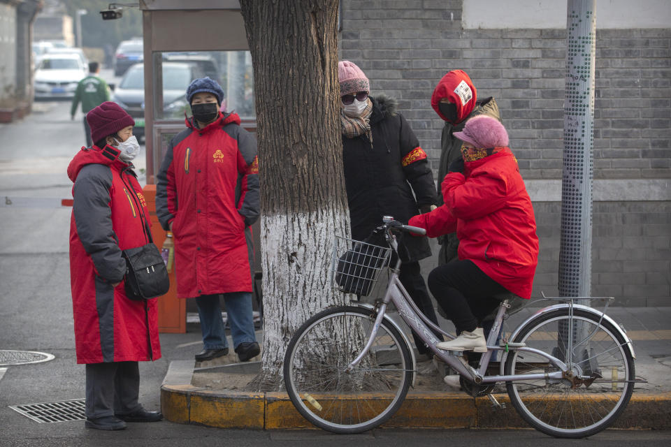 Neighborhood watch volunteers wear face masks as they gather on a street corner in Beijing, Monday, Jan. 27, 2020. China on Monday expanded sweeping efforts to contain a viral disease by postponing the end of this week's Lunar New Year holiday to keep the public at home and avoid spreading infection. (AP Photo/Mark Schiefelbein)