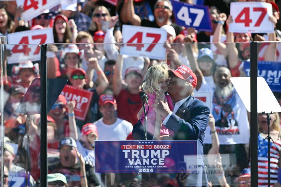 Donald Trump holds his granddaughter, Carolina, on stage at his Wilmington, North Carolina rally on Saturday (AFP via Getty Images)