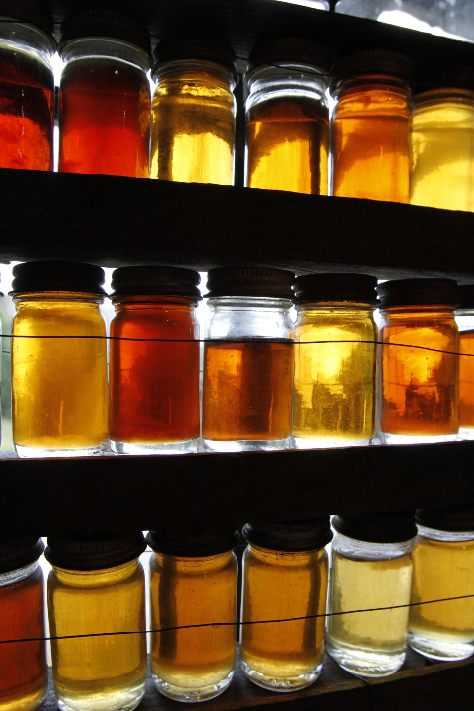 FILE-In this Oct. 27, 2011, file photo, bottles used to grade maple syrup sit in a window in East Montpelier, Vt. Vermonters have grown accustomed to their “fancy” “amber” and “grade B” types of maple syrup but new consumers may not be so sweet on the terms. So the country’s largest producer of the pancake topping is thinking of doing away with those terms and adopting new international names with flavor descriptions to help consumers delineate between four different colored and flavored syrups and to match new worldwide terms. The four classifications would be golden color, delicate taste; amber color, rich taste; dark color, robust taste; and very dark color, strong taste. (AP Photo/Toby Talbot)