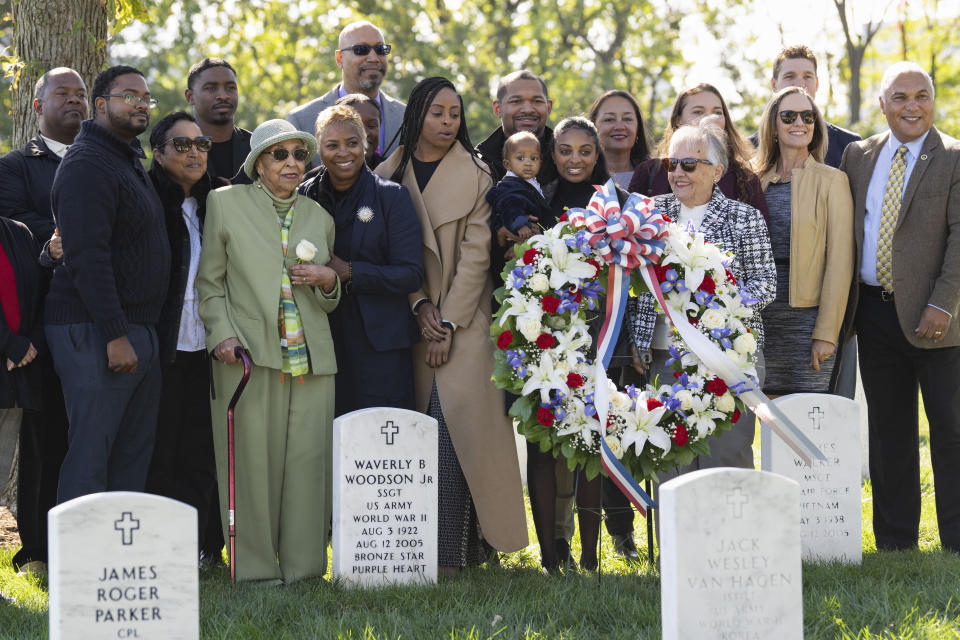 Joann Woodson, in green, is joined by family at the headstone of her husband, Cpl. Waverly B. Woodson Jr., following a ceremony at Arlington National Cemetery on Tuesday, Oct. 11, 2023 in Arlington, Va. During the D-Day invasion, the landing craft Cpl. Waverly B. Woodson Jr. was in took heavy fire and he was wounded before even getting to the beach, but for the next 30 hours he treated 200 wounded men while under intense small arms and artillery fire before collapsing from his injuries and blood loss, according to accounts of his service. (AP Photo/Kevin Wolf)