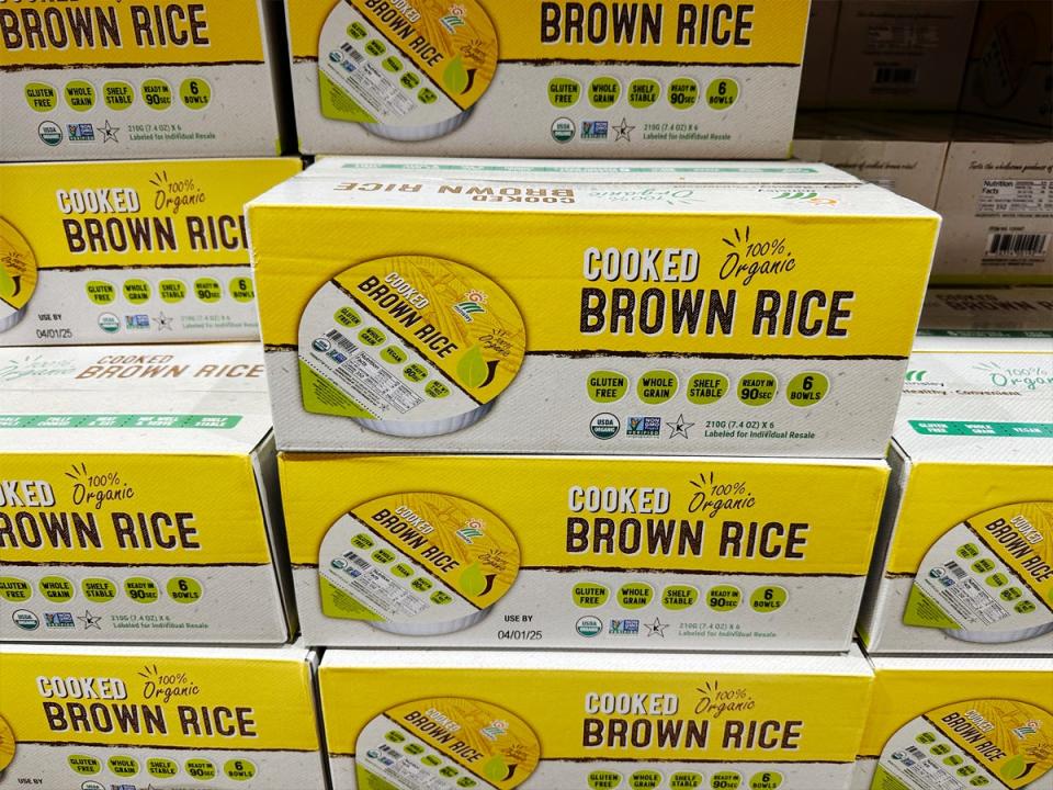 Tan and yellow boxes of cooked brown rice with an image of a package of cooked brown rice on the box