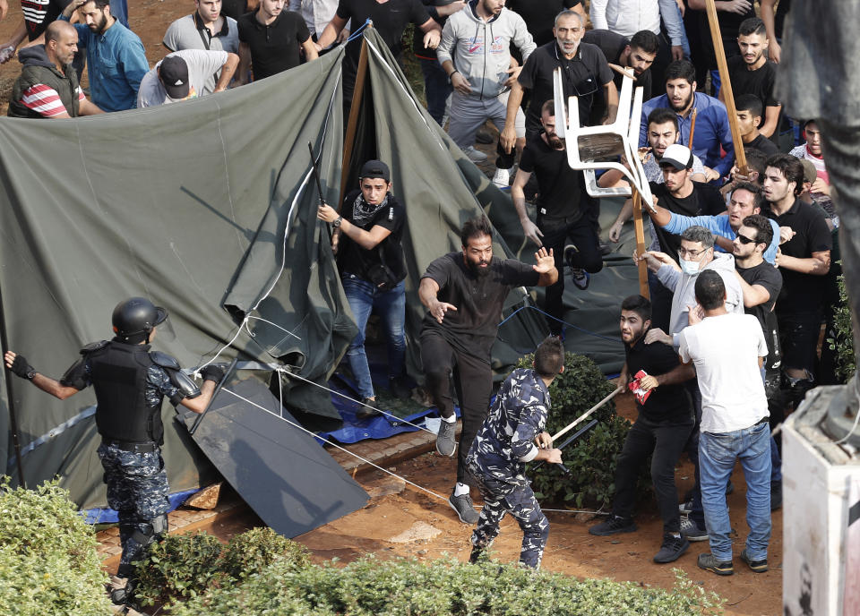 Hezbollah supporters, fights with Lebanese riot policemen, after a clashes erupted between Hezbollah supporters and anti-government protesters near the government palace, in downtown Beirut, Lebanon, Friday, Oct. 25, 2019. Hundreds of Lebanese protesters set up tents, blocking traffic in main thoroughfares and sleeping in public squares on Friday to enforce a civil disobedience campaign and keep up the pressure on the government to step down. (AP Photo/Hussein Malla)